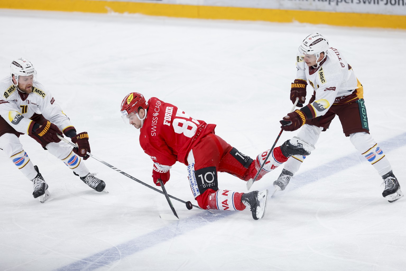 SC Rapperswil-Jona Lakers Dominic Lammer wird von Servettes Tanner Richard, links, und Servettes Noah Rod in die Zange genommen waehrend der Meisterschaftspartie der National League zwischen den SC Ra ...