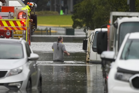 A man walks through flood waters back to his home from a fire truck at Windsor on the outskirts of Sydney, Australia, Tuesday, July 5, 2022. Hundreds of homes have been inundated in and around Austral ...
