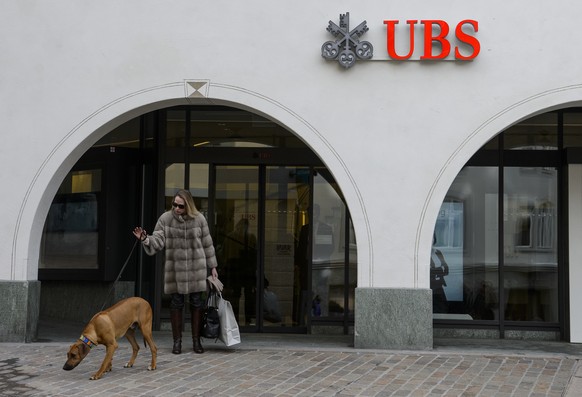 ARCHIVBILD ZUR BILANZ DER UBS IM ERSTEN QUARTAL 2017, AM FREITAG, 28. APRIL 2017 - A woman with her dog walks past a branch of the Swiss bank UBS in St. Moritz, Switzerland, Wednesday, March 16, 2016. ...