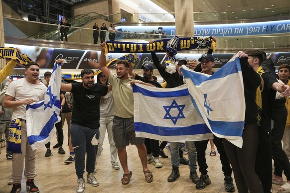 People welcome Maccabi Tel Aviv soccer fans as they arrive at Israel&#039;s Ben-Gurion International Airport on a flight from Amsterdam, where Israeli soccer fans were attacked following a match betwe ...