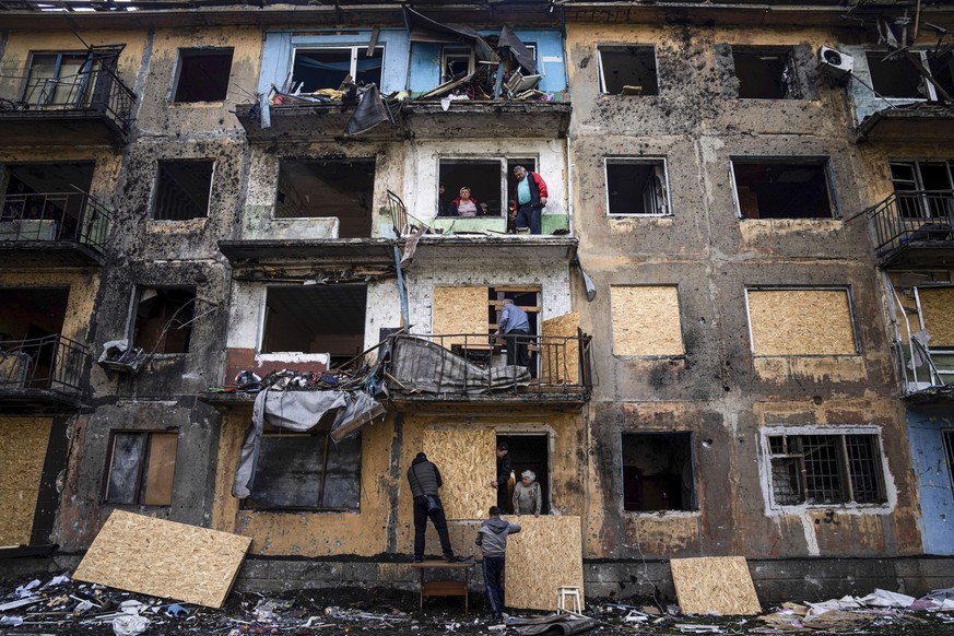 FILE - Local residents close the windows of an apartment building with plywood after Russian shelling in Dobropillya, Donetsk region, in eastern Ukraine, April 30, 2022. An interminable and unwinnable ...