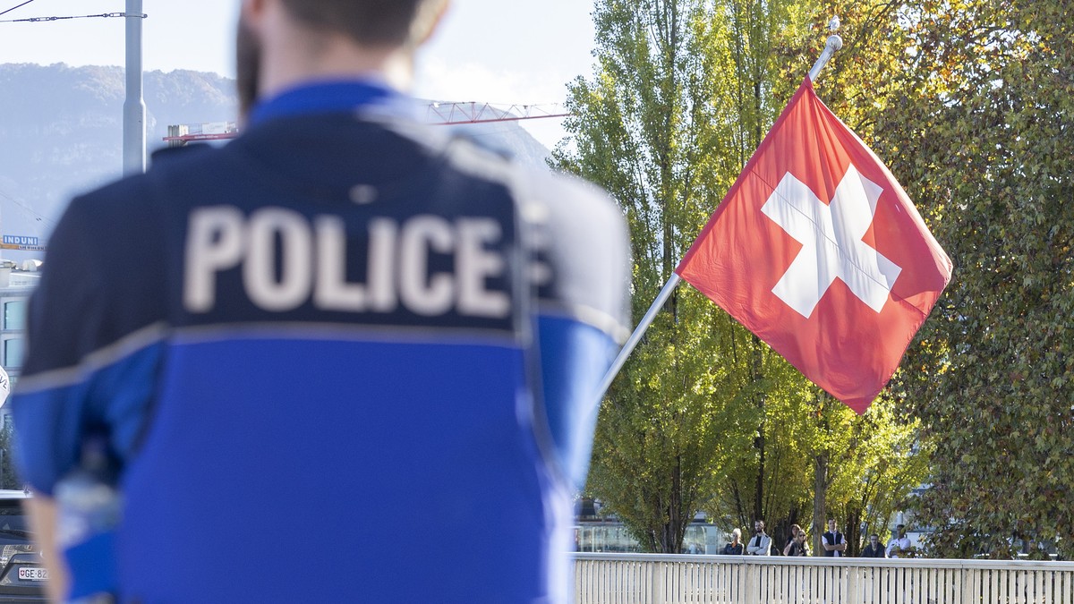 Swiss police officers controls the area where a climate activist from Renovate Switzerland have glued his hand to the ground during the "Renovate Switzerland" roadblock action at the pont du ...