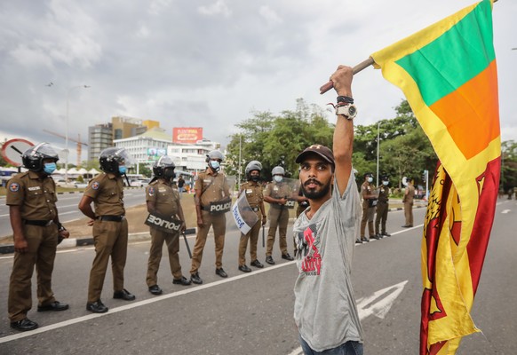 epa09873539 A man holds a Sri Lankan national flag during a protest, calling for the resignation of president over the alleged failure to address the economic crisis, outside the Parliament complex in ...