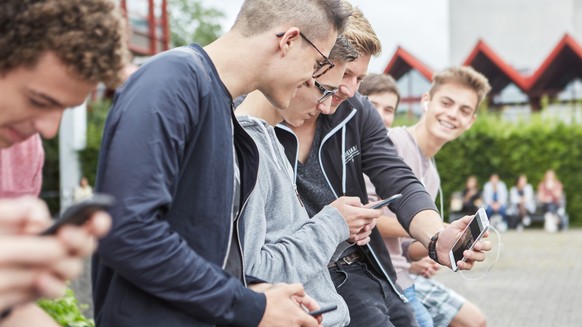 AZUM THEMA JUGENDLICHE UND MOBILTELEFON STELLEN WIR IHNEN HEUTE, DONNERSTAG, 14.01.2016, FOLGENDES BILDMATERIAL ZUR VERFUEGUNG --- group high school students use their smart phones on the schoolyard o ...