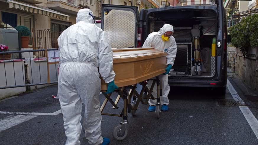 Medical staff wearing protective suits carry the coffin containing the body of Assunta Pastore, 87, after she passed away in her room at the Garden hotel in Laigueglia, northwest Italy, Liguria region ...