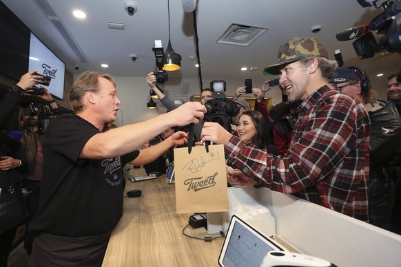 Canopy Growth CEO Bruce Linton, left to right, passes a bag with the first legal cannabis for recreation use sold in Canada to Nikki Rose and Ian Power at the Tweed shop on Water Street in St. John&#0 ...