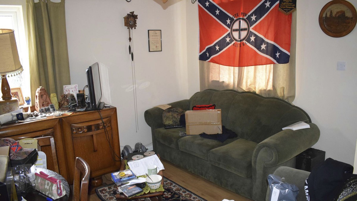 In this undated photo issued Monday Nov. 12, 2018, by Britain's West Midlands Police, showing Swastika cushions, slightly hidden below, and a Ku Klux Klan flag hanging in the lounge of the home o ...