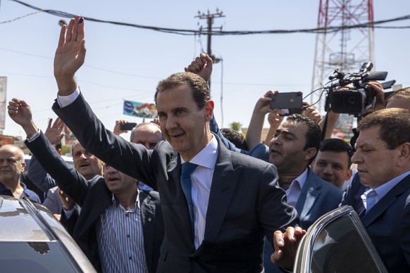 Syrian President Bashar Assad, center, waves to his supporters at a polling station during the Presidential elections in the town of Douma, in the eastern Ghouta region, near the Syrian capital Damasc ...
