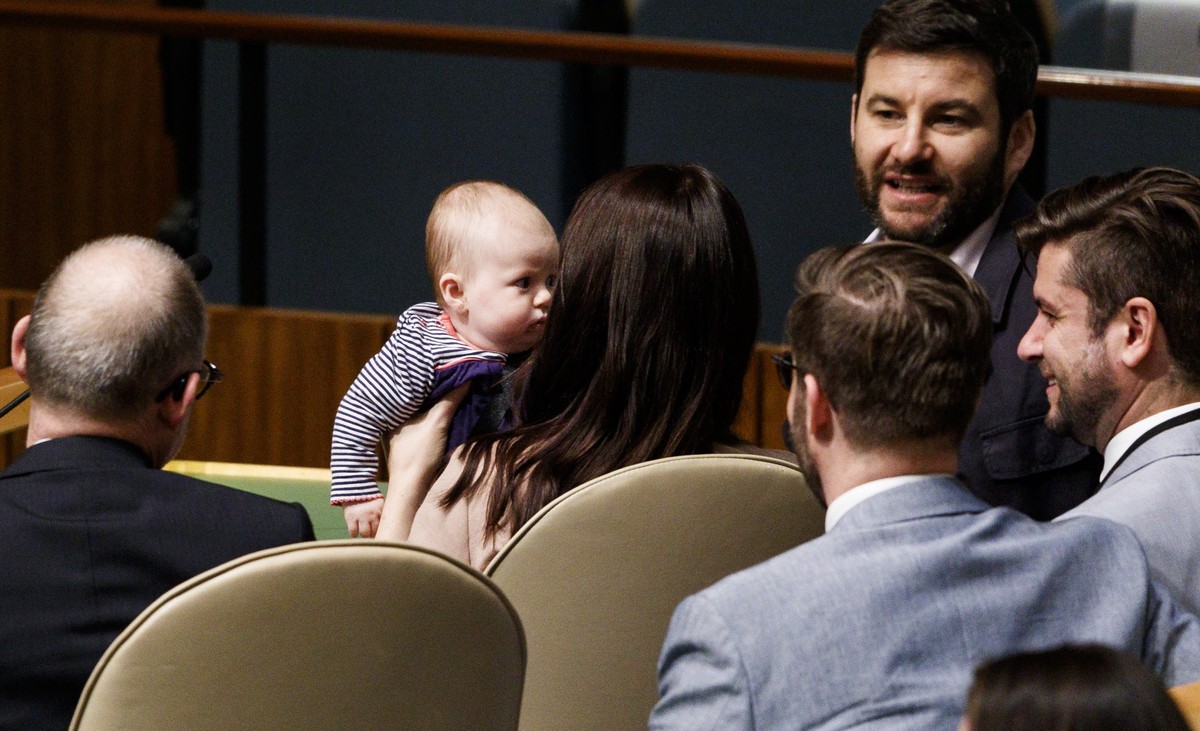 epa07043964 New Zealand Prime Minister Jacinda Ardern (C) holds her daughter Neve (C) while sitting with her partner Clarke Gayford (2-R) and her delegation after speaking at the Nelson Mandela Peace  ...