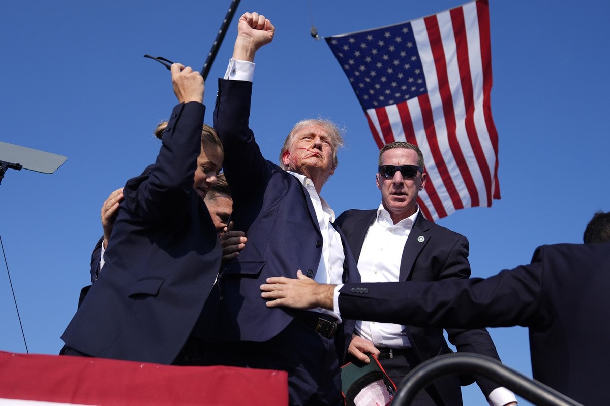Republican presidential candidate former President Donald Trump gestures as he is surrounded by U.S. Secret Service agents as he leaves the stage at a campaign rally, Saturday, July 13, 2024, in Butle ...