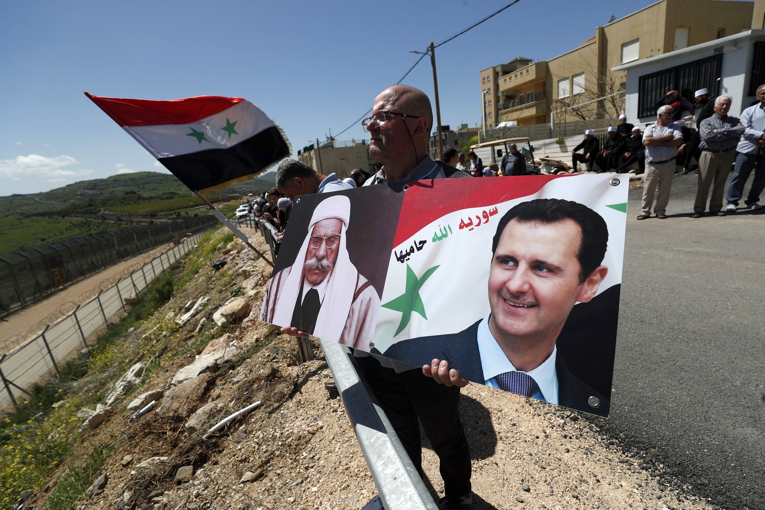 epa10576680 A Druze man holds portraits of Syrian President Bashar al-Assad (R) and Druze leader and Syrian nationalist Sultan al-Atrash (L) as people gather next to the ceasefire line between Israel  ...
