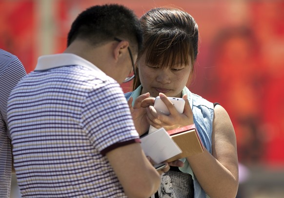 Chinese people use their smartphone on Tiananmen Square in Beijing, China Wednesday, May 28, 2014. China is targeting popular smartphone-based instant messaging services in a month-long campaign to cr ...