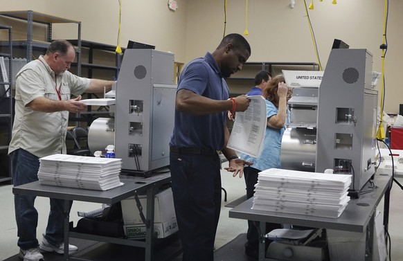 Election workers place ballots into electronic counting machines, Sunday, Nov. 11, 2018, at the Broward Supervisor of Elections office in Lauderhill, Fla. The Florida recount began Sunday morning in B ...