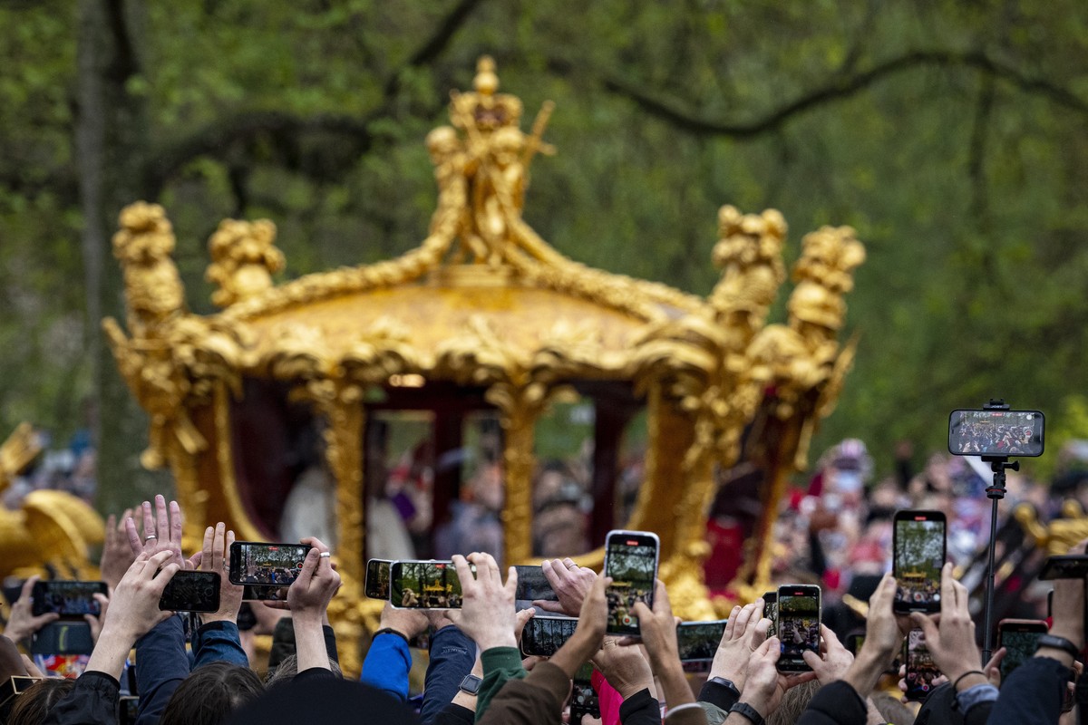 People use their mobile phones as Britain's King Charles III and Queen Camilla ride in the Gold State Coach, returning from the coronation ceremony, in London, Saturday, May 6, 2023. (AP Photo/An ...