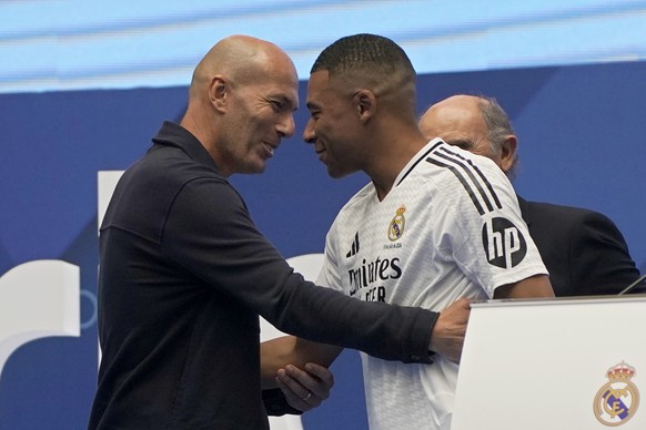Kylian Mbappe, of France, embraces former French player Zinedine Zidane, left, while being presented to fans as a new Real Madrid player at the Santiago Bernabeu stadium in Madrid, Tuesday, July 16, 2 ...