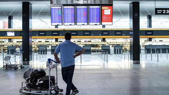 A passenger is looking at the departures board at the Zurich Airport in Zuerich, Switzerland, Tuesday, March 10, 2020. The spreading of the Coronavirus has effects on the passenger volume at Switzerla ...