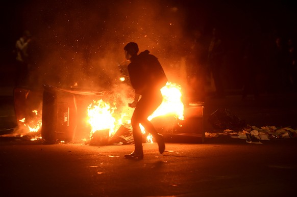 A woman passes burning garbage during a demonstration in Oakland, California, U.S. following the election of Donald Trump as President of the United States November 9, 2016. REUTERS/Noah Berger