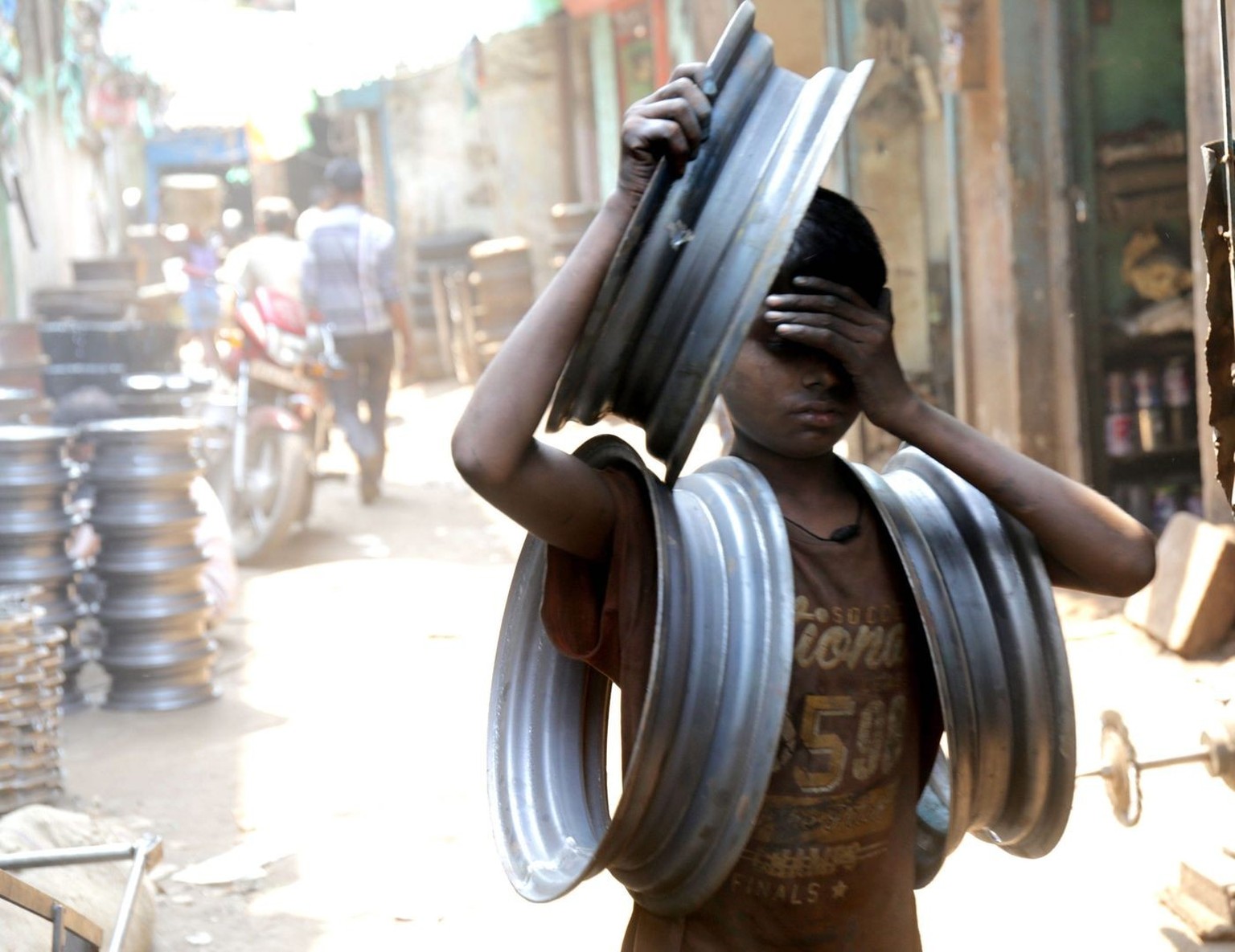 epa05349272 (18/32) A boy carries car wheels at a local auto mobile recycle market in Calcutta, eastern India, 23 May 2016. Child labour occurs largely in the rural and informal economy, according to  ...