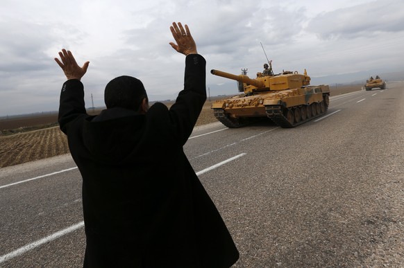 epa07078129 A man waves to Turkish soldiers on tanks near the Syrian-Turkish border, at Reyhanli district in Hatay, Turkey, 21 January 2018. Reports state that the Turkish army is on an operation name ...