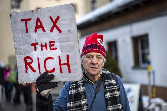 Phil White of Patriotic Millionaires holds a placard reading &quot;Tax the rich&quot; as he attends a demonstration before the annual meeting of the World Economic Forum, WEF, in Davos, Switzerland, o ...