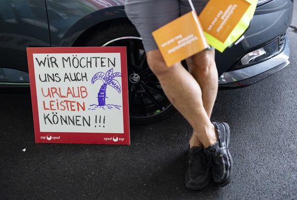 Ein Angestellter des Flugzeugabfertigers Swissport protestiert am Samstag, 23. Juli 2022 am Flughafen Zuerich Kloten mit einem Plakat mit der Aufschrift �Wir moechten uns auch Urlaub leisten koennen�  ...