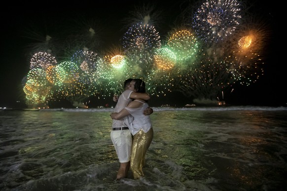 People celebrate the start of the New Year, backdropped by fireworks exploding in the background over Copacabana Beach in Rio de Janeiro, Brazil, early Sunday, Jan. 1, 2023. (AP Photo/Bruna Prado)