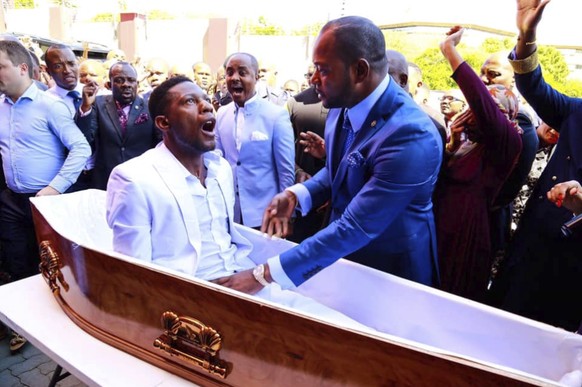 Der Mann, setzt sich im Sarg auf. Die Menge jubelt.