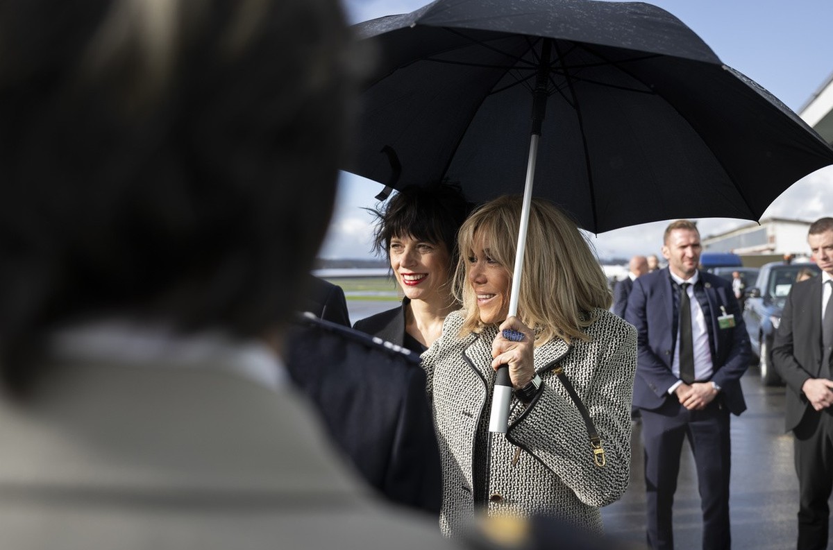 France's First Lady Brigitte Macron, right, and Switzerland's First Lady Muriel Zeender Berset, left, smile under an umbrella after greeting the delegations, at the Bern-Belp Airport in Belp ...