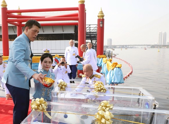 epa08965747 Thai King Maha Vajiralongkorn Bodindradebayavarangkun (L) accompanied by the Royal Consort Sineenat Wongvajirapakdi (2-L) release fishes into the Chao Phraya River during a merit-making ce ...