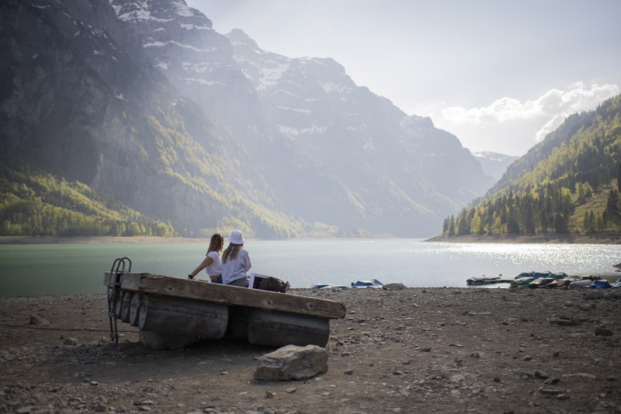 Zwei Frauen sitzen am Klöntalersee in Glarus, der einen unterdurchschnittlich tiefen Wasserstand im April 2020 führt.