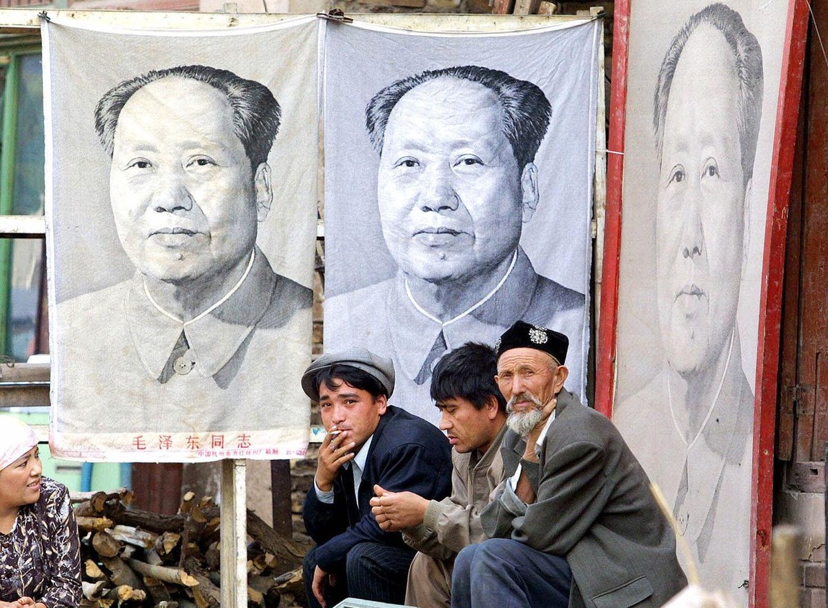 Three Muslim Uighur men rest outside a store where they sell portraits and memorabilia of late communist leader Chairman Mao Zedong, in Kashgar, in China's western Xinjiang province in this Sept. ...