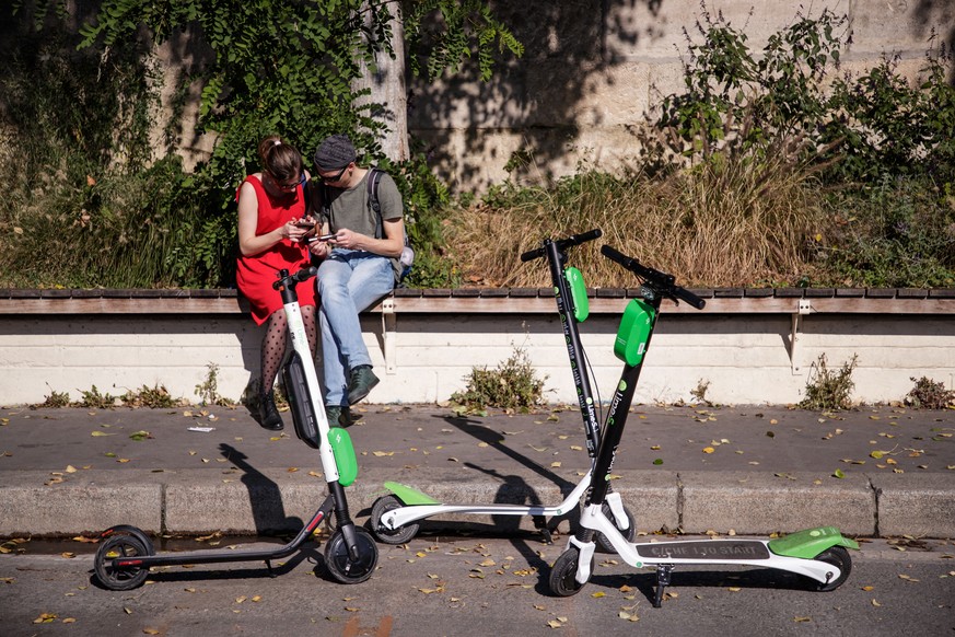 epa07083630 A couple uses a phone application to rent electric scooters of US company Lime in Paris, France, 10 October 2018. A free float of electric vehicle service is available to users in Paris. E ...