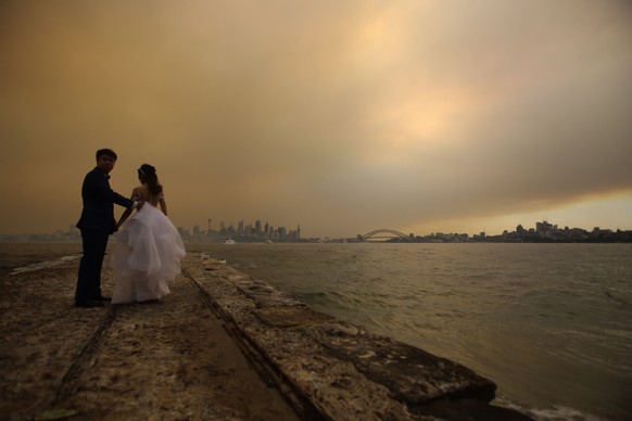 epa08045950 A couple poses for wedding photos as smoke haze from bushfires in New South Wales engulfs Sydney, Australia, 05 December 2019. Emergency warnings were issued on 05 December for bushfires i ...