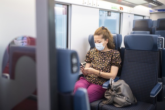 Eine Frau mit Atemschutzmasken faehrt mit dem Zug vom Hauptbahnhof in Zuerich, aufgenommen am Montag, 6. Juli 2020. (KEYSTONE/Ennio Leanza)