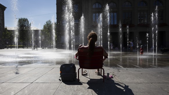 Jovana aus Serbien sitzt vor dem Brunnen auf dem Bundesplatz, am Dienstag, 22. August, 2023 in Bern. (KEYSTONE/Peter Klaunzer)