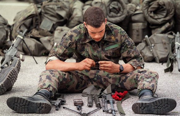 Rekruten der Territorial Infanterie RS in Belchen nach dem 40km Marsch im Ziel in Muemliswil, aufgenommen im Maerz 2000. Rekrut bei der Zerlegung und Reinigung der Waffe nach der Ueberlebenswoche. (KE ...