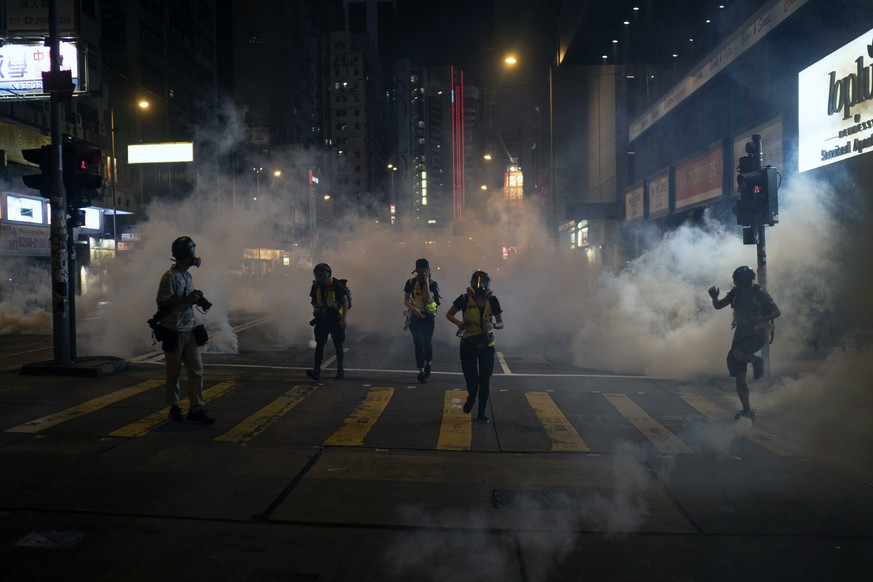 Emergency responders and journalists run from tear gas during a protest in Hong Kong on Friday, Oct. 4, 2019. Masked protesters streamed into Hong Kong streets Friday after the city&#039;s embattled l ...