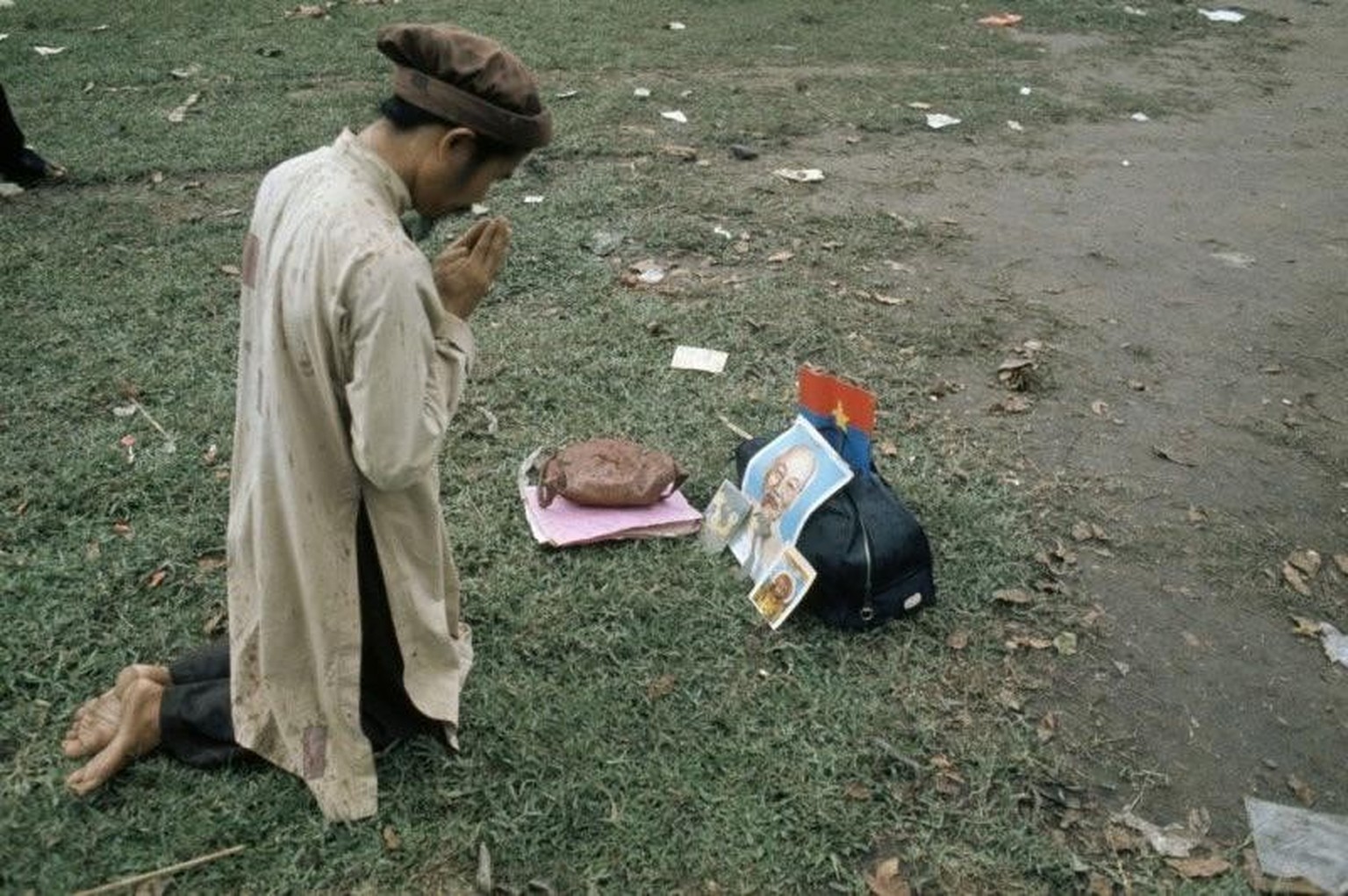 The prayer of a Vietnamese. Next to the image of the Buddha is a large portrait of Ho Chi Minh. 1975