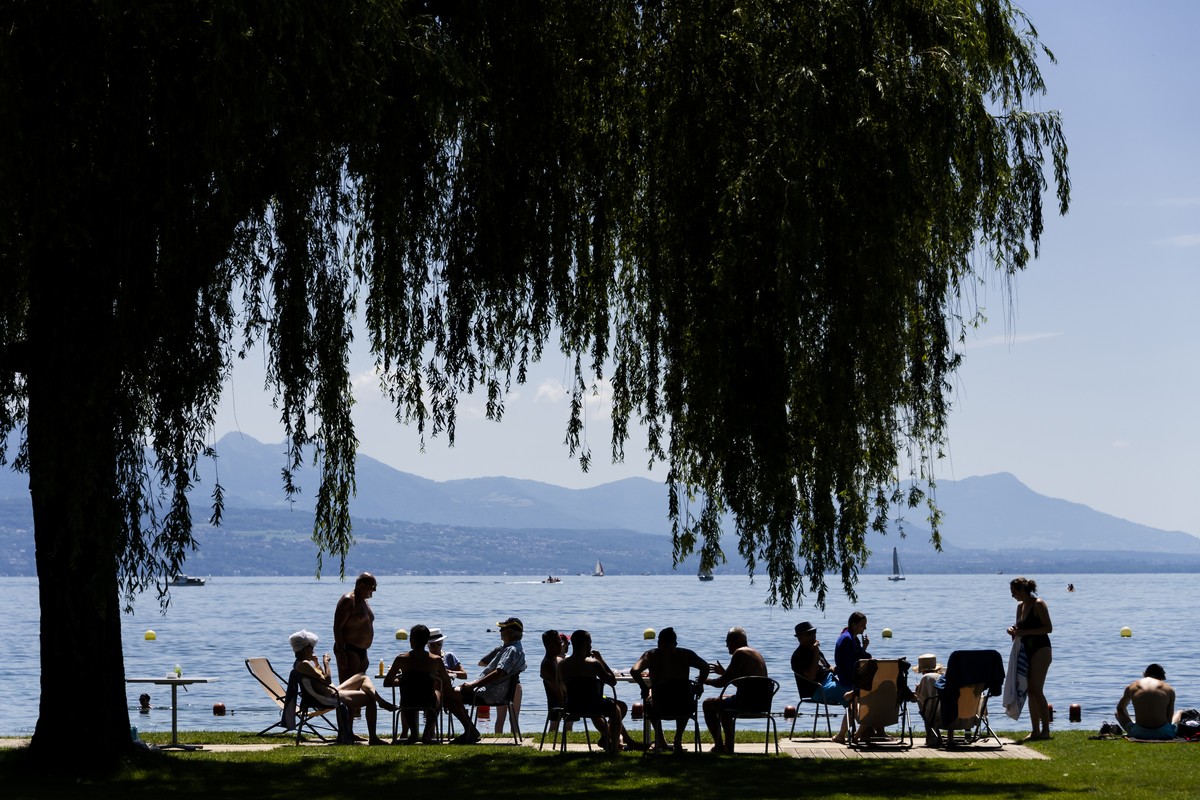 Des personnes prennent le soleil sur une pelouse de la piscine de Bellerive au bord du lac Leman a l'occasion des vacances d'ete le samedi 10 juillet 2021 a Lausanne. (KEYSTONE/Jean-Christop ...