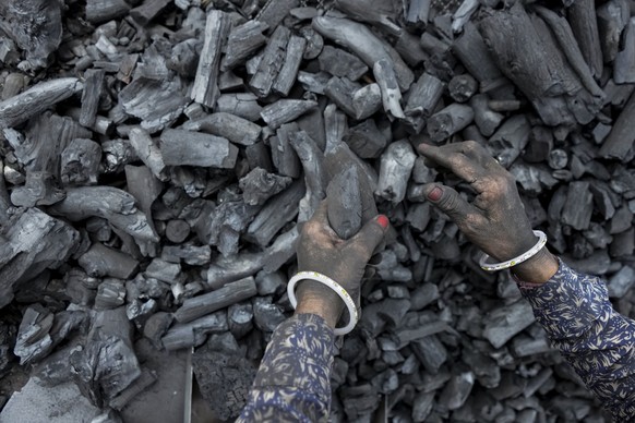 A woman works at a coal depot in Ahmedabad, India, Monday, May 2, 2022. An unusually early and brutal heat wave is scorching parts of India, where acute power shortages are affecting millions as deman ...