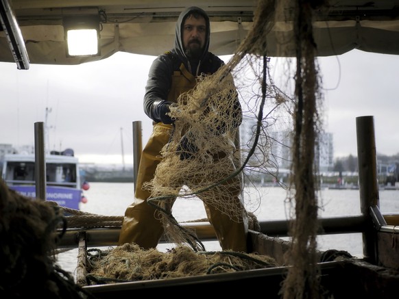 Fisherman Nicolas Bishop of the Jeremy-Florent II fishing boat cleans a net at the port of Boulogne-sur-Mer, northern France, Thursday, Dec. 10, 2020. Fishing rights are a sticking point in negotiatio ...