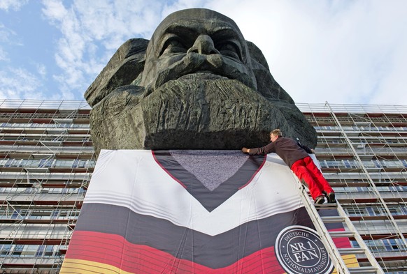 Worker Michael Six fixes a huge German soccer jersey around the monument of former German philosopher and and revolutionary socialist Karl Marx before the start of the soccer match Germany vs Ghana du ...