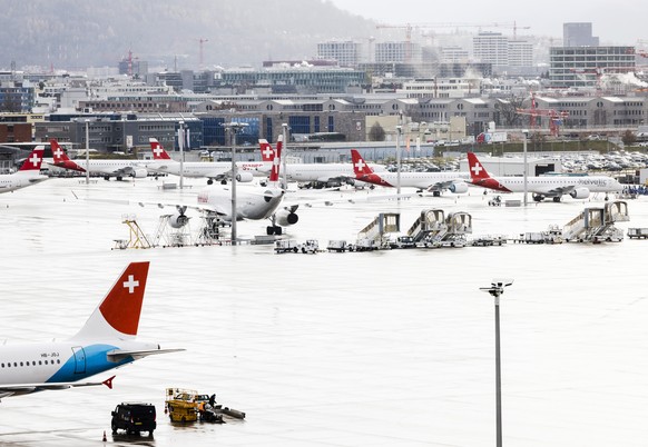 Flugzeuge der Swiss und der Helvetic Airways stehen am Flughafen Zuerich Kloten mit Glattbrugg, Oerlikon und Seebach im Hintergrund, aufgenommen am Donnerstag, 2. Dezember 2021 in Zuerich. (KEYSTONE/M ...