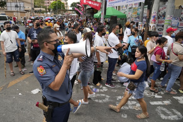 A police officer tries to control a crowd outside a polling station as they try to enter to cast their votes in the Tondo district of Manila, Philippines on Monday, May 9, 2022. About 67 million regis ...