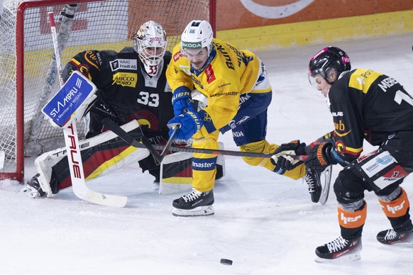Torhueter Sandro Zurkirchen (SCB), links, und Waltteri Merelae (SCB), rechts, kaempfen um den Puck mit Valentin Nussbaumer (HCD) im Spiel der Eishockey National League zwischen SC Bern, SCB, und HC Da ...