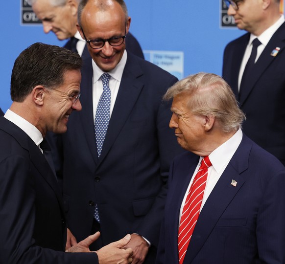 President Donald Trump, center front, speaks with NATO Secretary General Mark Rutte, front left, and Germany&#039;s Chancellor Friedrich Merz, second left, during a group photo of NATO heads of state  ...