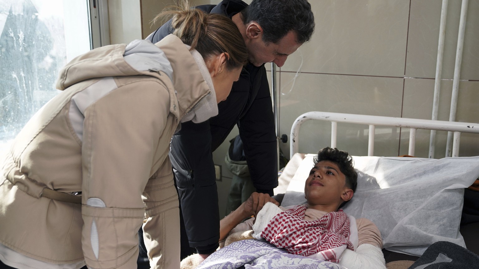 In this photo released by the official Syrian state news agency SANA, Syrian President Bashar Assad, center, and his wife Asma visit a wounded survivor of devastating earthquake, at a hospital in Alep ...