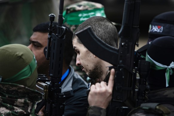 epa11882188 Palestinian fighters from Hamas&#039;s Izz ad-Din al-Qassam Brigades escort Israeli hostages Ohad Ben-Ami, Or Levi (pictured) and Eli Sharabi onto the stage before handing them over to a R ...