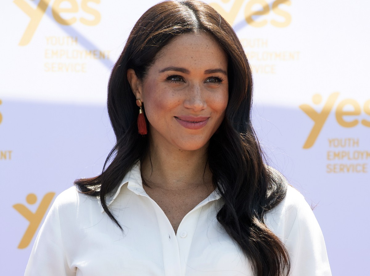 epa07888552 Britain's Meghan, the Duchess of Sussex, reacts to Prince Harry (unseen), the Duke of Sussex, delivering a speech as they visit the Tembisa township to learn about the 'Youth Emp ...