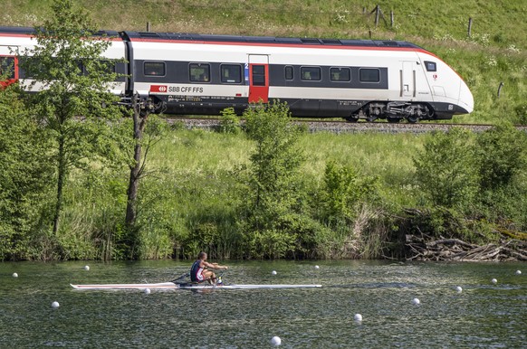 Ein Ruderer aus Daenemark beim Training sowie ein Zug der SBB auf Vorbeifahrt am Rotsee anlaesslich des Ruder Weltcups auf dem Rotsee in Luzern am Mittwoch, 22. Mai 2024. (KEYSTONE/Urs Flueeler)